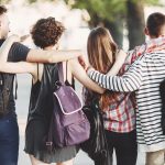 friends with backpacks hugging walking in the city