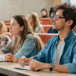 In the Classroom Multi Ethnic Students Listening to a Lecturer and Writing in Notebooks. Smart Young People Study at the College.